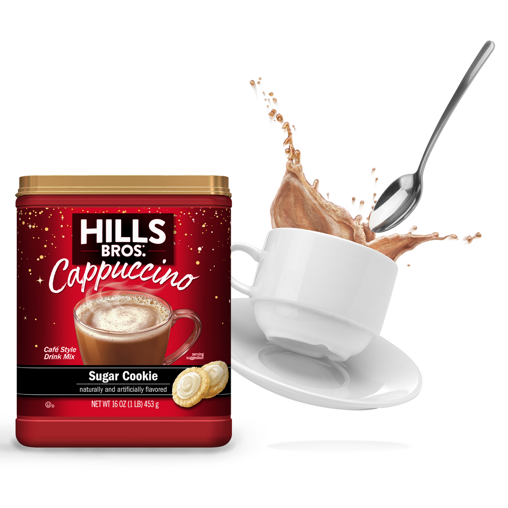 A jar of Hills Bros. Sugar Cookie Cappuccino Mix next to a cup of Hills Bros. Cappuccino with a spoon causing a splash, all against a white background.