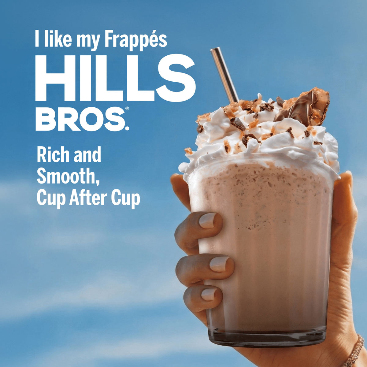 A hand holds a glass of Frappés Salty Caramel topped with whipped cream and chocolate pieces against a blue sky, featuring Hills Bros. Frappes branding and single serve frappé drink mix text beside it.