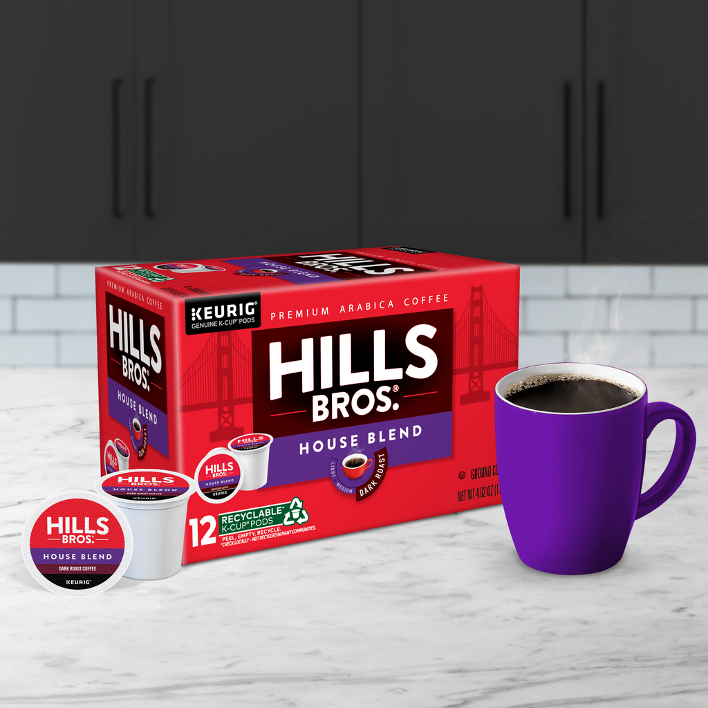 A box of Hills Bros. Coffee House Blend - Dark Roast Keurig K-Cup® Pods, made from premium Arabica beans, sits on a kitchen countertop next to a steaming purple mug.