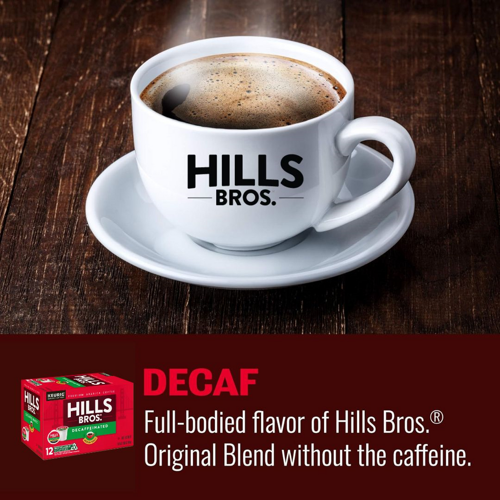 A white coffee cup on a saucer labeled "Hills Bros." rests on a wooden table. Text reads: "Decaf Blend—enjoy the rich taste of Hills Bros.® Original Blend without caffeine, made from premium Arabica beans." Product: Decaf Blend - Medium Roast - K-Cup® Pods by Hills Bros. Coffee.