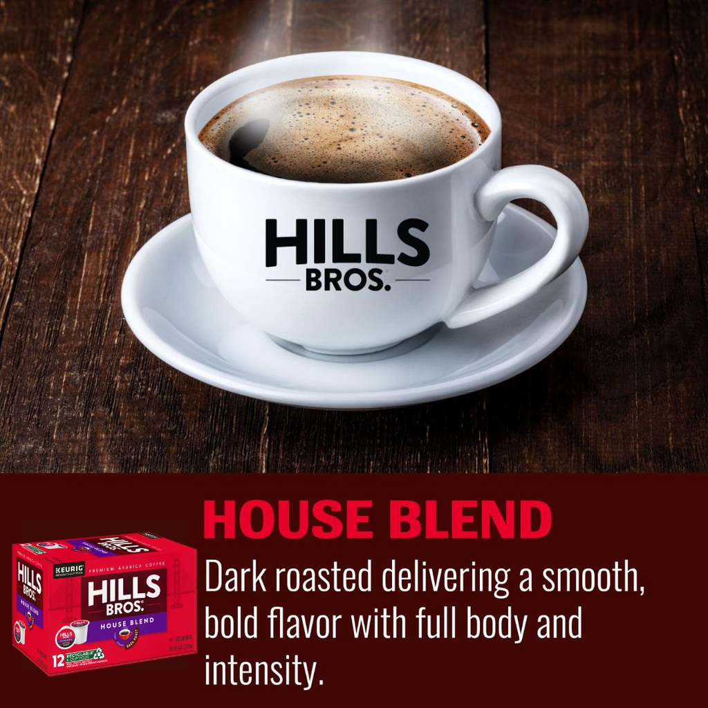 A white cup of Hills Bros. Coffee rests on a wooden table. Below it is a red box of House Blend - Dark Roast - Keurig K-Cup® Pods, offering a dark roast made from premium Arabica beans for a smooth, bold flavor.