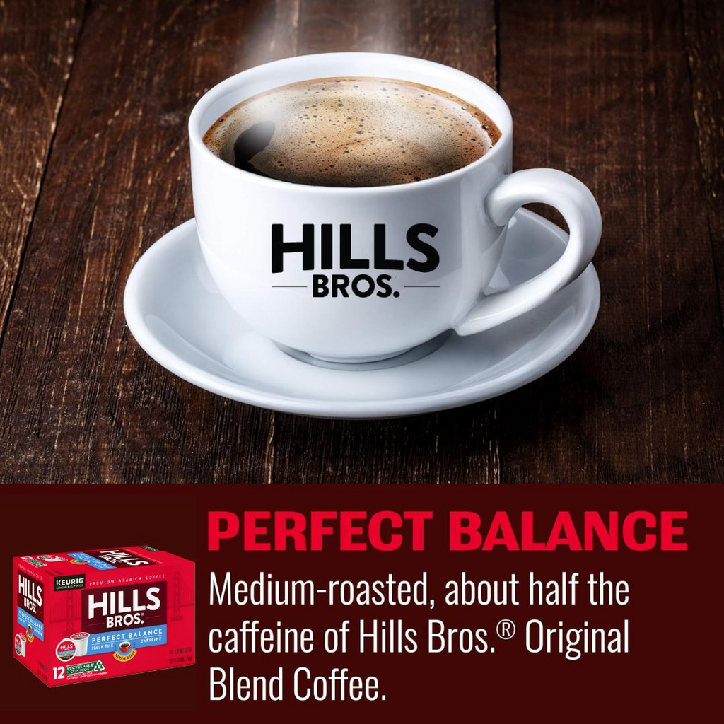 A Keurig K-Cup® Pod of Hills Bros. Coffee's Perfect Balance - Medium Roast rests on a wooden table, its box beside it. Crafted from premium Arabica beans, this medium-roasted delight provides half the caffeine.