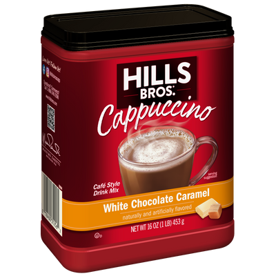 A red container of Hills Bros. Cappuccino White Chocolate Caramel - Instant Cappuccino Mix, featuring an image of a cappuccino in a clear mug. Net weight: 16 oz (1 lb) / 453 g.