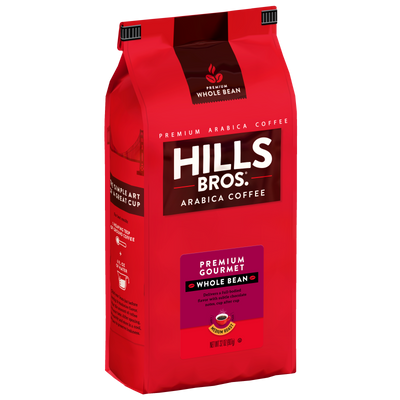 A red bag of Hills Bros. Coffee labeled “Premium Gourmet - Medium Roast - Whole Bean - Premium Arabica,” featuring premium Arabica coffee beans, includes brewing instructions and a coffee cup image on the side. This blend is gluten free.