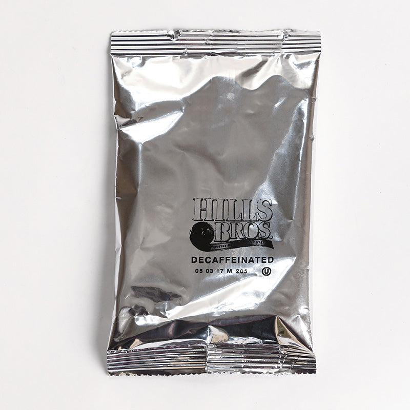 A silver foil packet of Hills Bros. Coffee Decaf Original Blend - Medium Roast - Ground on a white surface.